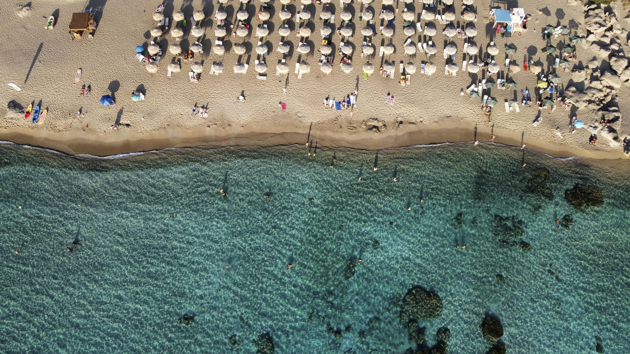 areal shot of sun umbrellas, people at the beach and the ocean
